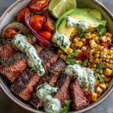 Platter-style presentation of the Steak, Avocado, and Roasted Corn Bowl, featuring juicy meat, Cotija cheese crumbles, and lime wedges for a Tex-Mex inspired dinner.