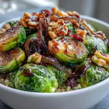 A wholesome vegetarian dinner featuring a hearty roasted Brussels sprouts bowl, garnished with toasted walnuts and tart dried cranberries.