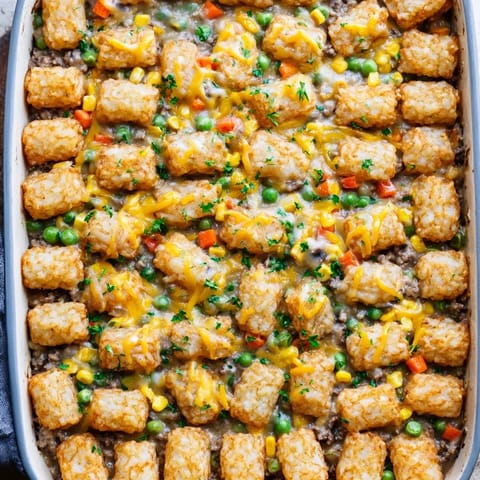 Hearty tater tot casserole serving suggestion, plated with a fresh green side salad for dinner.