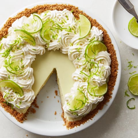 A chilled Key Lime Pie slice on a white plate, garnished with lime zest, ready for a sunny dessert table. 