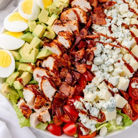 Colorful Cobb Salad platter with diced tomatoes, hard-boiled eggs, blue cheese crumbles, and tangy red wine vinaigrette. 