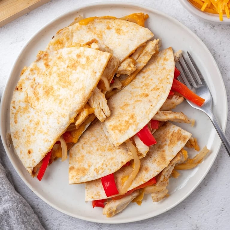Sautéed red bell peppers and onions with grilled chicken filling peek out from the warm, golden-brown Chicken Quesadilla.