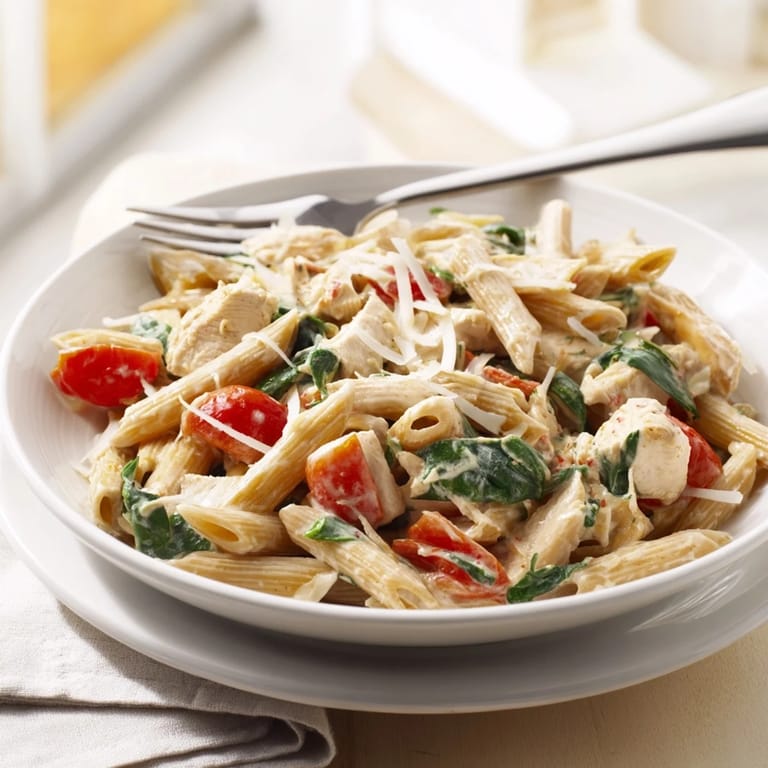 Savory skillet-cooked chicken and wilted spinach tossed with Greek Yogurt Chicken Pasta, offering a comforting, protein-rich meal for a family of four.