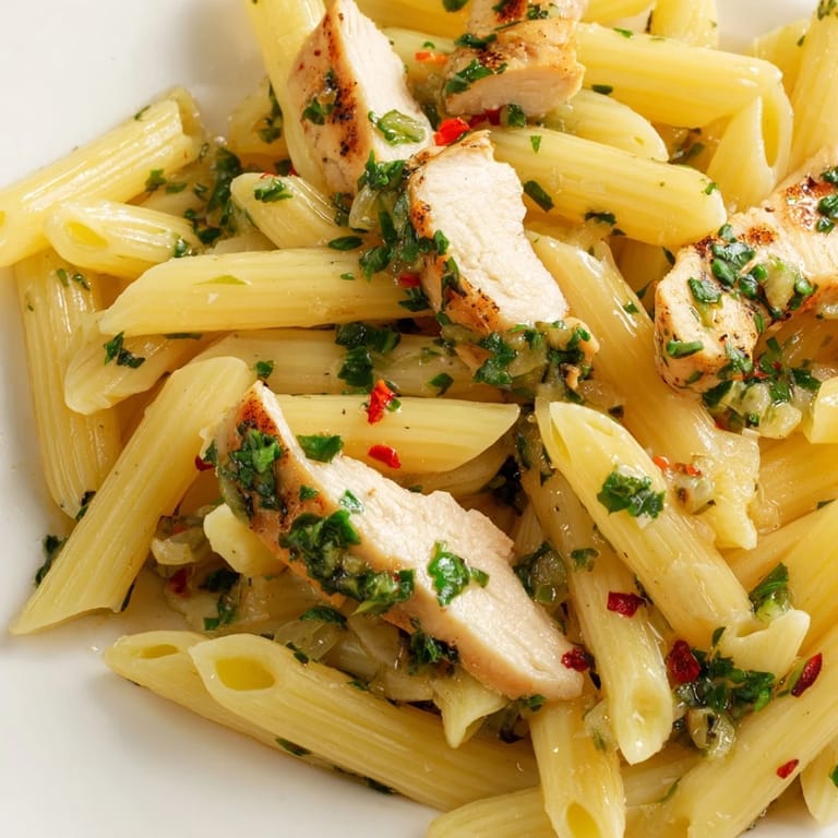A close-up of Chimichurri Chicken Pasta highlights fresh parsley and garlic specks in the herby sauce over tender noodles.